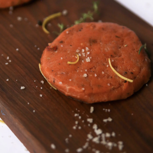 OUr Garden Style Salmon Burger on top of a wooden chopping board with some garnish